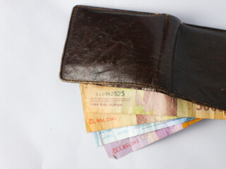 isolated worn brown leather wallet containing several Indonesian rupiah notes