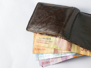 isolated worn brown leather wallet containing several Indonesian rupiah notes