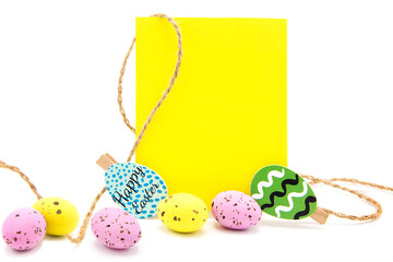 Greeting blank card with rope on clothespins with scattered colored eggs isolated on a white background. Copy space. Free space for text. Happy easter!	