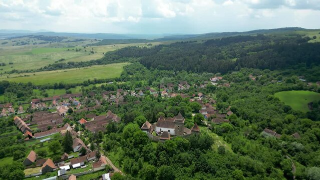 Viscri - Beautiful saxon village in the heart of Romania. Famous travel destination. Green landscape, agriculture fields. Drone circling around the village