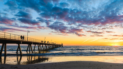 Glenelg Beach pier with walking people silhouettes at sunset at sunset, South Australia