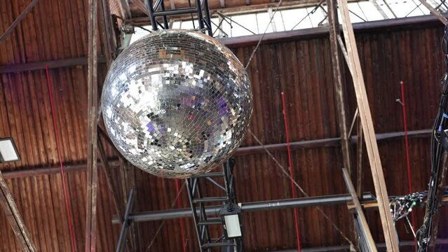 Shimmering Disco Ball. A gleaming disco ball hangs from the ceiling, reflecting an array of lights, adding vibrancy to a spacious setting
