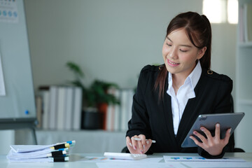 Portrait of beautiful asian young Business woman working audit and calculating expense annual financial report balance sheet statement,doing finance making notes on paper graph data checking document.