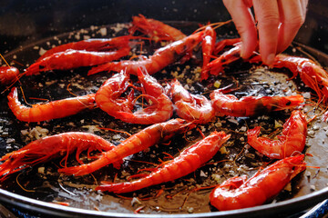 Cooking shrimp in a frying pan. Roasting shrimp for paella.