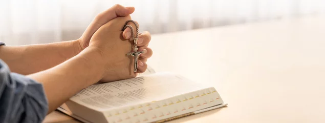 Tuinposter Asian male folded hand prayed on holy bible book while holding up a pendant crucifix. Spiritual, religion, faith, worship, christian and blessing of god concept. Blurring background. Burgeoning. © Summit Art Creations