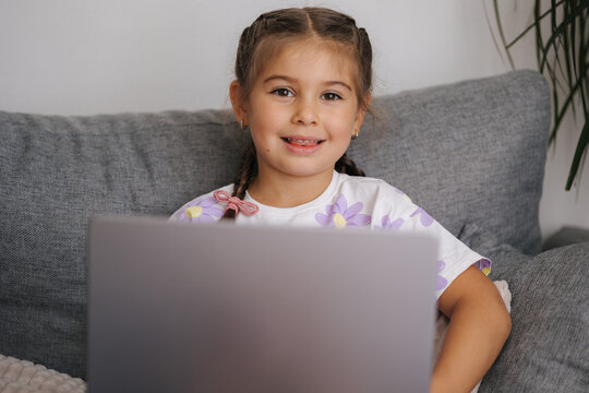 Portrait of beautiful little girl using smart devise. Five year old girl open and use laptop