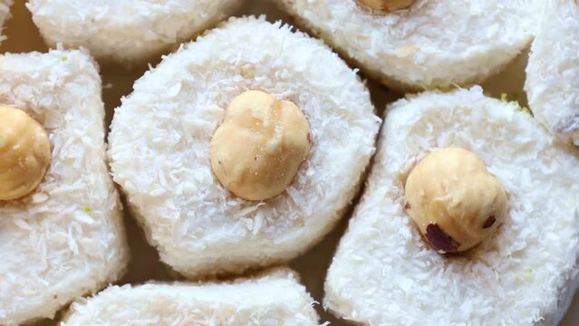 Sweet white Turkish delights or lokum with hazelnuts and coconut circle rotation close up top view
