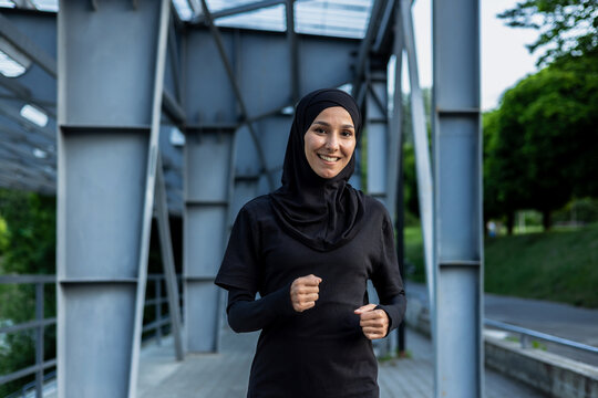 An active woman in hijab running on a city bridge, depicting health, fitness, and an active lifestyle. - Powered by Adobe