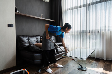 cleaning service housekeeper women swipe floor in living room. House cleaning service concept - obrazy, fototapety, plakaty