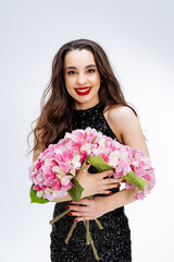 Beautiful brunette girl with bouquet of pink flowers in her hands