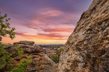 the mesmerizing hues of sunset sky, casting warm light over the textured rocky foreground and...