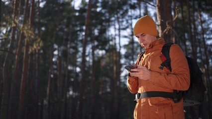 travel navigation. man tourist looking for a way in a smartphone navigation in winter in a forest park. male hacker close-up navigates in the forest navigation looking for a way in winter in park - 767010851