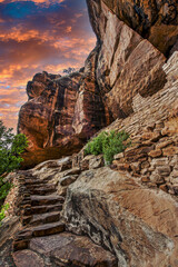 An awe-inspiring staircase carved into a rock face leading towards a dramatic, fiery sky at sunset
