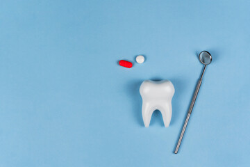 Tooth, dental instruments and painkillers on a blue background. A concept for dentists, dental...