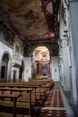 Interior perspective in low light of the church Santa Maria Maddalena dei Pazzi with wooden benches and altar in the background, Florence ITALY