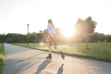 Back view of young woman rollerblading in the park