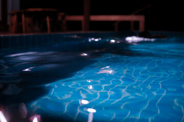 The background image of the water surface in the pool creates lights in the pool at night. Swimming pool with blue tile floor