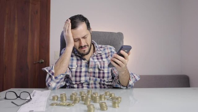 Worried man does accounting on his calculator. Broke businessman accounts money coins. Frustration.