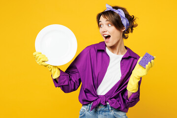 Young surprised amazed woman wear purple shirt rubber gloves casual clothes do housework tidy up...