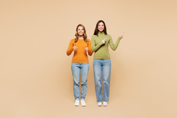Full body happy young friends two women they wear orange green shirt casual clothes together point...