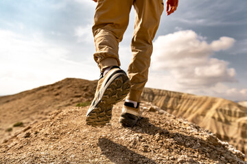 Close up photo of hiker legs and boots is walking uphill against blue sky