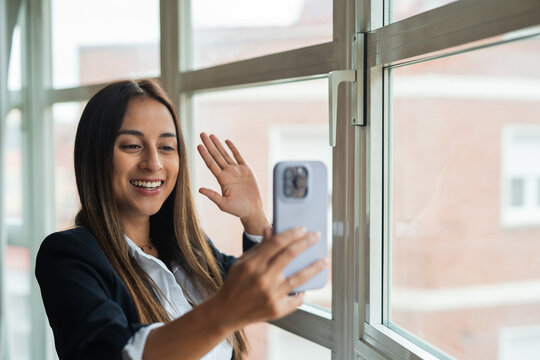 Smiling woman taking selfie by a window