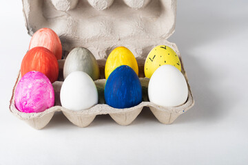 Colorful painted Easter eggs on a cardboard tray on a white background. Easter concept.