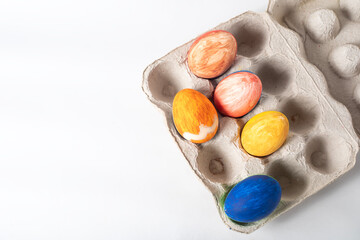 Colorful painted Easter eggs on a cardboard box on a white background