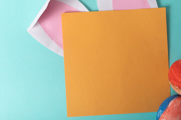 Easter concept. Colorful blank paper card with copy space for your message or text. Easter eggs, Easter bunny ears, top view.