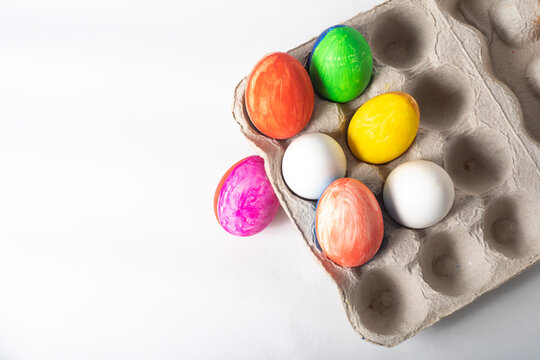 Colorful painted Easter eggs on a cardboard box on a white background