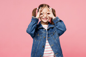 Little child smiling cute kid girl 7-8 years old wearing denim shirt have fun cover eyes with fingers pov glasses isolated on plain pastel pink background. Mother's Day love family lifestyle concept.