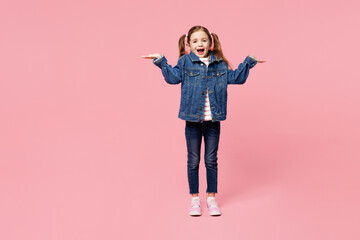 Full body little child kid girl 7-8 years old wears denim shirt have fun shrugging shoulders looking puzzled spread hands isolated on plain pink background. Mother's Day love family lifestyle concept.