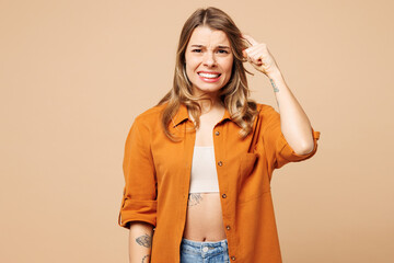 Young shocked mistaken sad Caucasian woman wear orange shirt casual clothes look camera hold...