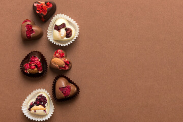 chocolate sweets in the form of a heart with fruits and nuts on a colored background. top view with space for text, holiday concept