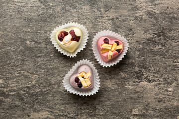 chocolate sweets in the form of a heart with fruits and nuts on a colored background. top view with space for text, holiday concept