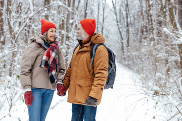 Fototapeta na wymiar Mature couple in a snowy forest feeling excited