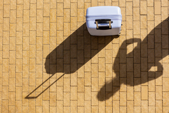 Suitcase casting shadow on airport runway pavement