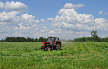 Traktor koszący trawę na łące, sianokosy - obrazy, fototapety, plakaty