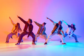 Foto op Plexiglas Dansschool Group of five dancers in casual clothes performing with synchronized poses against gradient studio background in neon light. Concept of modern dance style, hobby, active lifestyle, youth culture