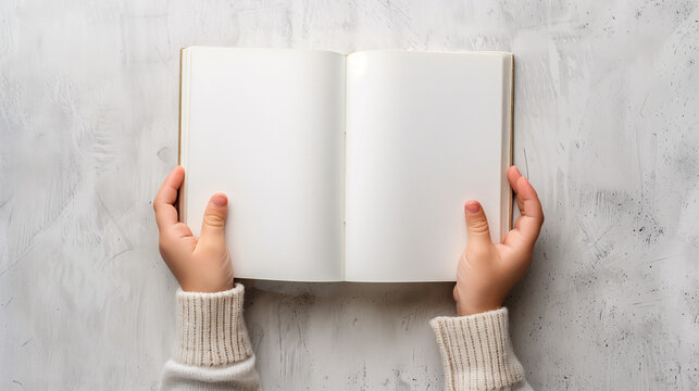 A close-up of a kid's hand is opening blank pages of a notebook with copy-space for text on a light gray background. Background for kids and children.