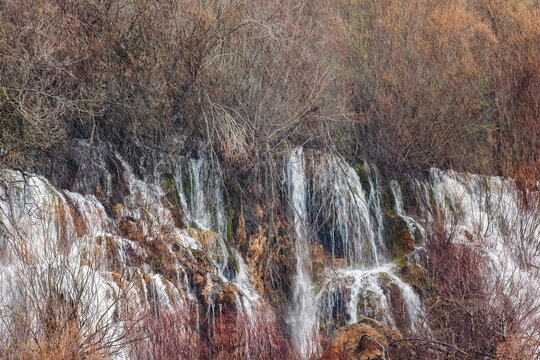 Cascading waterfall amidst bare winter trees