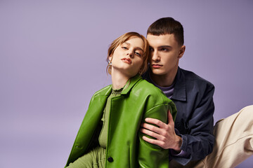 appealing stylish woman in green jacket sitting on floor with her boyfriend and looking at camera