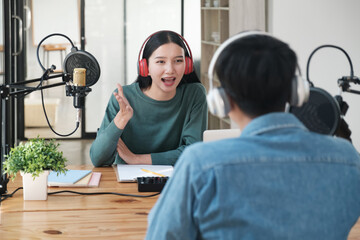A woman and a man are talking to each other in a studio. The woman is wearing headphones and smiling