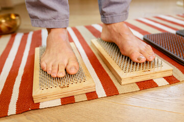 morning yoga practice with sadhu nails. mans foot on the wooden desk with sharp metal nails - obrazy, fototapety, plakaty
