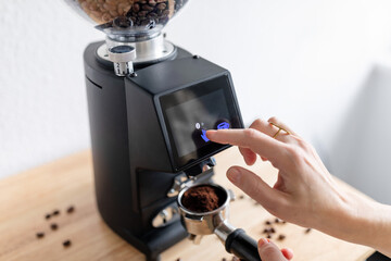 Woman barista make grinding coffee beans with machine