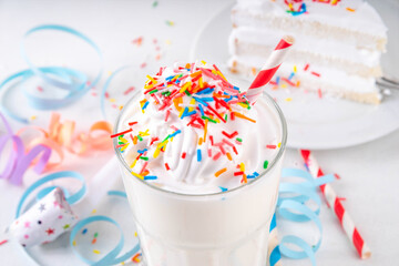 Fototapeta na wymiar Birthday cake milkshake or smoothie drink. Frozen homemade Birthday cake white vanilla ice cream floating cocktail with whipped cream, and colorful sugar sprinkles, funfetti