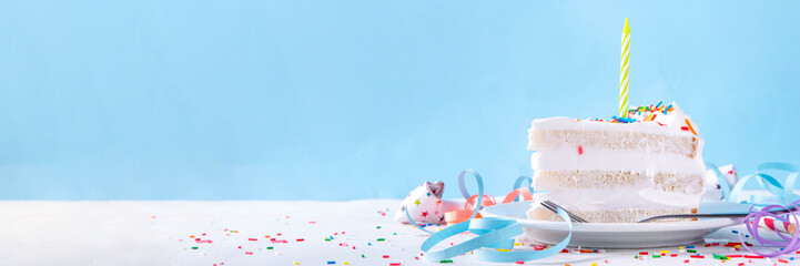 Birthday cake slice on birthday party decorated table.  Slice of Birthday Cake with white whipped cream, sugar sprinkles funfetti and candle, copy space