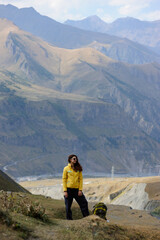 Fototapeta premium Standing woman hiker in yellow jacket and sunglasses in high mountains 