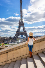 A tourist woman enjoys the view from Trocadero to the Eiffel Tower of Paris, France, on a sunny day