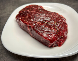 Raw marbled steak on white plate